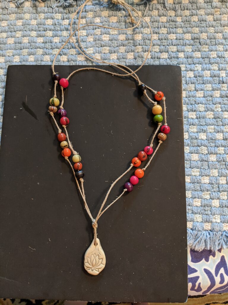 Simple acai bead necklace with ceramic pendant.